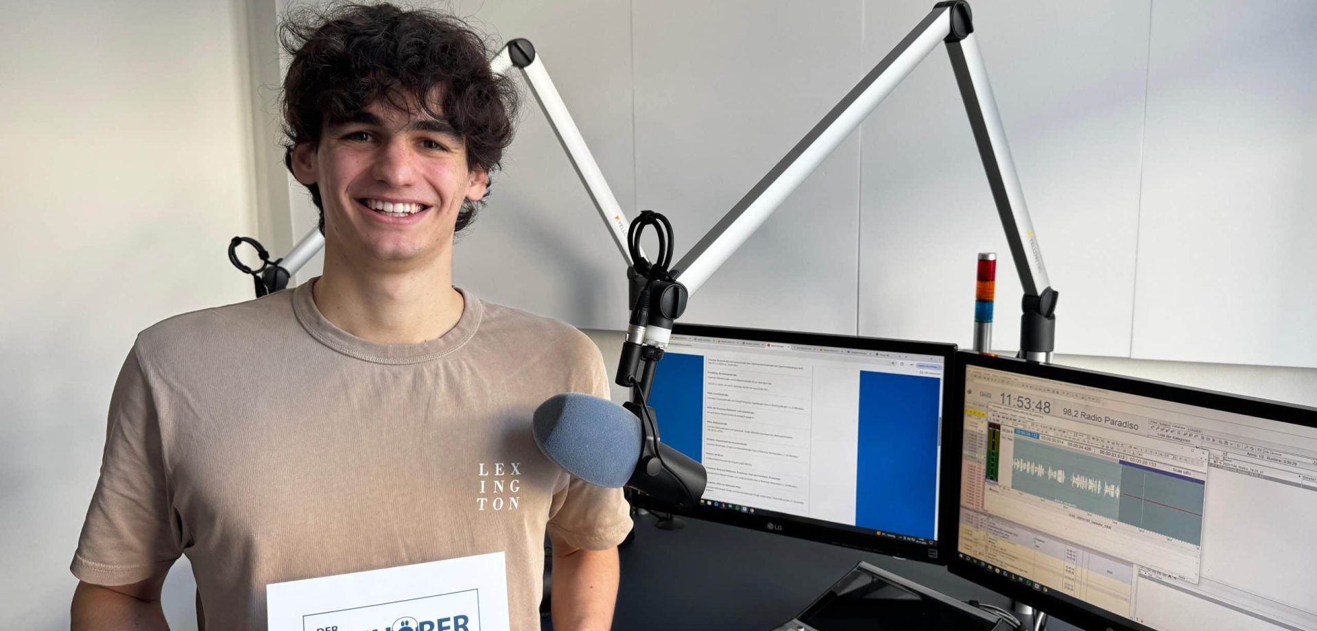 Lars Bergmann im Radiostudio- Er hält seine Hinhörer-Urkunde in der Hand.
